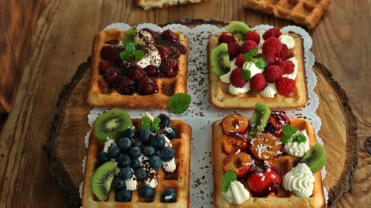 Pyszne gofry belgijskie z owocami: malinami, borówkami, kiwi i śliwkami. Idealne na deser, gdy szukasz inspiracji na gofry belgijskie przepis.