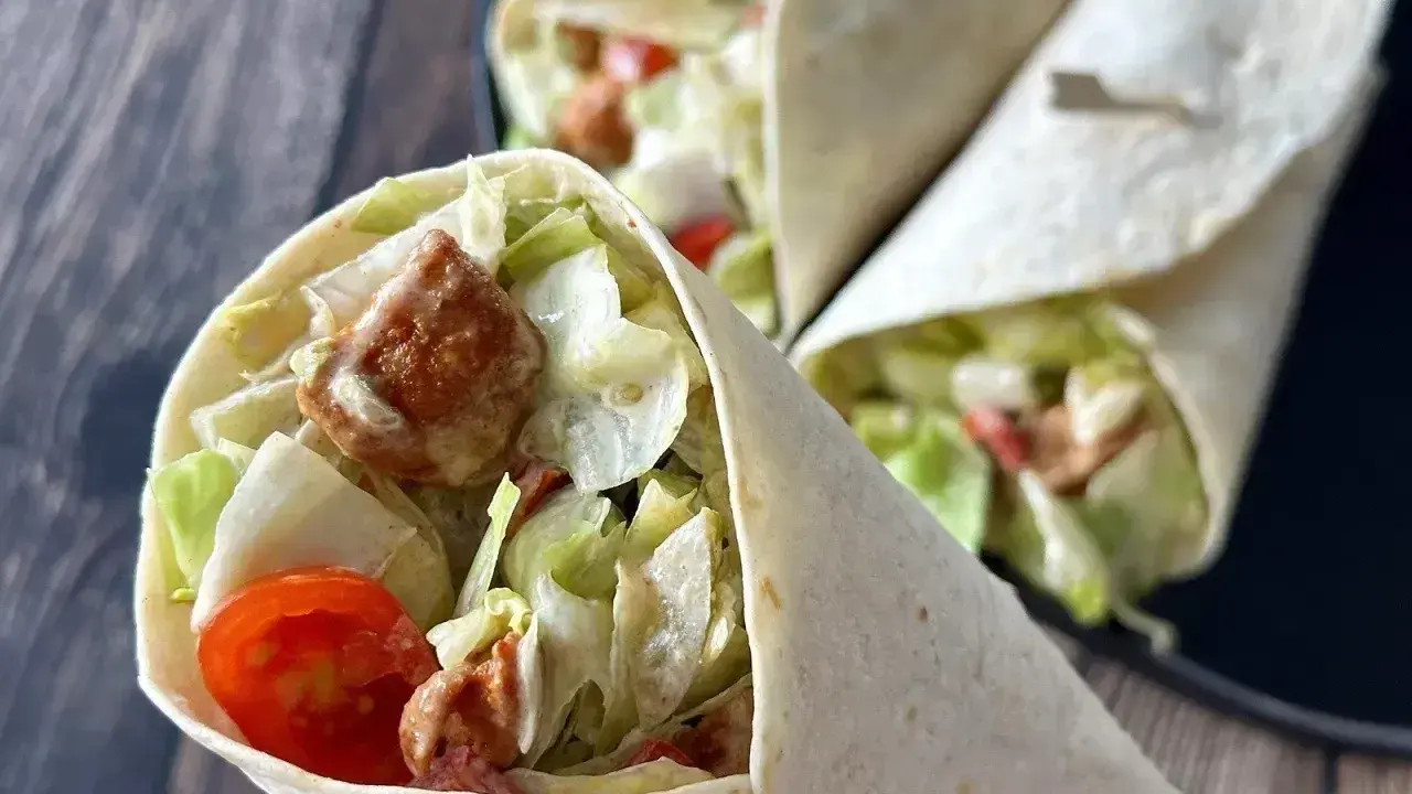Pyszna tortilla z kurczakiem, chrupiącą sałatą i pomidorkami. Idealna na szybki lunch.