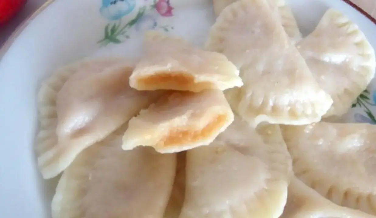 Pyszne pierogi z jabłkami, jeden rozkrojony ukazuje słodkie nadzienie.