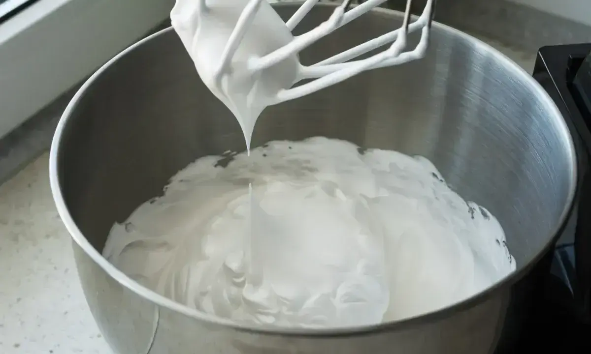 Ubita masa z mascarpone i białek, gotowa do przygotowania pysznego ciasta bez pieczenia.