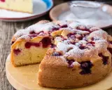Puszyste ciasto jogurtowe z owocami, posypane cukrem pudrem, wygląda apetycznie. Idealne na deser!