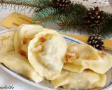 Pyszne pierogi z mięsem i kapustą, ozdobione gałązkami świerku i szyszkami, wyglądają jak świąteczny przysmak.