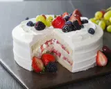 Pyszny tort z bitą śmietaną i mascarpone, przełożony truskawkami i owocami leśnymi. Udekorowany świeżymi owocami.