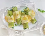 Pyszne cannelloni ze szpinakiem, zapieczone pod kremowym sosem serowym, ozdobione listkami bazylii.