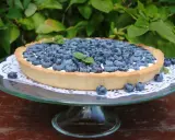 Letnia tarta z borówkami, pełna świeżych owoców, kusi apetycznym wyglądem. Idealna na deser w ogrodzie.