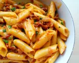 Penne z sosem z suszonych pomidorów i zieloną cebulką, danie wygląda apetycznie.