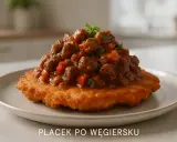 Sycący placek po węgiersku, polany gęstym gulaszem z mięsa i papryki, ozdobiony natką pietruszki.