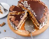 Pyszny tort snickers bez pieczenia, udekorowany czekoladą i wiórkami. Idealny na deser!