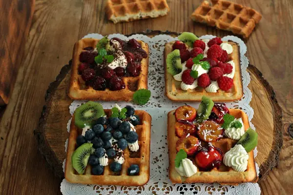 Pyszne gofry belgijskie z owocami: malinami, borówkami, kiwi i śliwkami. Idealne na deser, gdy szukasz inspiracji na gofry belgijskie przepis.