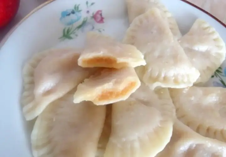 Pyszne pierogi z jabłkami, jeden rozkrojony ukazuje słodkie nadzienie.